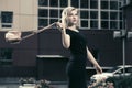 Happy young fashion blond woman in black dress walking in city s Royalty Free Stock Photo