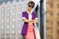 Young fashion business woman in purple blazer and sunglasses walking in city street Royalty Free Stock Photo