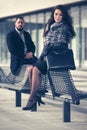 Happy young fashion couple sitting on bench on city street Royalty Free Stock Photo