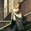 Happy young fashion woman in gray sleeveless coat and white sweater