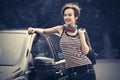Happy young fashion woman with handbag leaning on her car Royalty Free Stock Photo