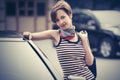 Happy young fashion woman with pixie hair leaning on her car Royalty Free Stock Photo