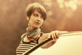 Happy young fashion woman with pixie hair leaning on her car Royalty Free Stock Photo