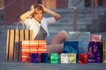 Happy young fashion woman with shopping bags sitting on sidewalk Royalty Free Stock Photo