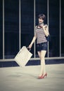 Happy young fashion woman with shopping bags walking next to mall