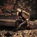 Happy young fashion woman sitting on wooden bridge in autumn park Royalty Free Stock Photo