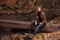 Happy young fashion woman sitting on wooden bridge in autumn park Royalty Free Stock Photo