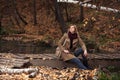 Happy young fashion woman sitting on wooden bridge in autumn park Royalty Free Stock Photo