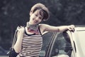 Happy young fashion woman in striped tank top leaning on her car Royalty Free Stock Photo