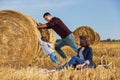 Happy young father and his two year old girl pushing a hay bale