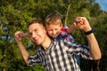 Little boy is sitting on shoulders his dad while imitating the f Royalty Free Stock Photo