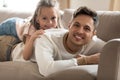 Happy young father lying on couch with smiling small daughter. Royalty Free Stock Photo