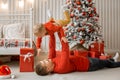 Happy young father lying on the floor near the New Year tree and a lot of present boxes at christmas time and holding his funny Royalty Free Stock Photo