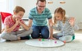 Happy young father plays with his two cheerful siblings children Board Game with colorful dices Royalty Free Stock Photo