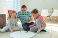 Happy young father plays with his two cheerful siblings children Board Game with colorful dices