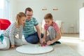 Happy young father plays with his two cheerful siblings children Board Game with colorful dices