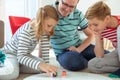 Happy young father plays with his two cheerful siblings children Board Game with colorful dices Royalty Free Stock Photo