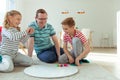 Happy young father plays with his two cheerful siblings children Board Game with colorful dices Royalty Free Stock Photo