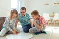 Happy young father plays with his two cheerful siblings children Board Game with colorful dices