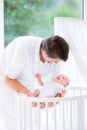 Happy young father putting newborn baby in crib Royalty Free Stock Photo