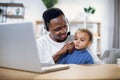 Happy father sitting with baby son and working on laptop Royalty Free Stock Photo