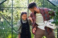 Happy young father with small daughter working outdoors in backyard, gardening and greenhouse concept. Royalty Free Stock Photo
