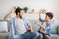 Happy young father and teen son giving high-five while watching soccer match at home Royalty Free Stock Photo