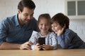 Happy young father using cellphone with small kids. Royalty Free Stock Photo