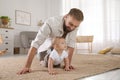 Happy young father watching his cute baby crawl on floor at home Royalty Free Stock Photo