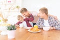 Happy young fathers and son have breakfast in the kitchen, gay family with a child, time together, parenting in homosexual