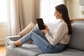 Smiling young woman using tablet on couch at home