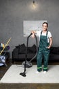 happy young female cleaning company worker leaning at vacuum cleaner and smiling Royalty Free Stock Photo