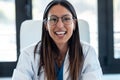 Happy young female doctor smiling and looking at camera while sitting in the consultation Royalty Free Stock Photo