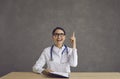 Happy young female doctor struck by a cool idea smiling and pointing her finger up Royalty Free Stock Photo