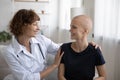 Happy young female doctor supporting bald patient. Royalty Free Stock Photo