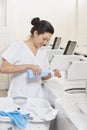 Happy young female employee pouring detergent in washing machine Laundromat Royalty Free Stock Photo