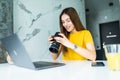 Happy young female executive looking at camera in creative office. Freelance photographer woman with camera at home office editing Royalty Free Stock Photo