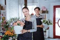 happy young female florist wearing apron holding bucket flower smiling looking at camera. working in flower shop Royalty Free Stock Photo