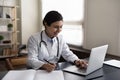 Happy young female indian doctor working in modern clinic office.