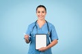 Happy young female nurse presenting digital tablet with blank screen, ideal for healthcare apps or medical offers Royalty Free Stock Photo