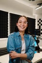 Happy young female radio host smiling while broadcasting in studio Royalty Free Stock Photo