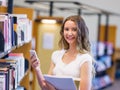 Happy female student holding books at the library Royalty Free Stock Photo