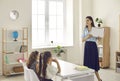 Happy young female teacher showing her elementary school students a new book in class