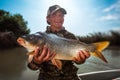 Happy young fisherman holds the big Carp fish Royalty Free Stock Photo