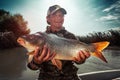 Happy young fisherman holds the big Carp fish Royalty Free Stock Photo