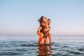 Happy young fit couple embrace each other with love in the sea or ocean at summer sunset. Romantic mood, tenderness, relationship