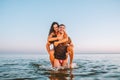 Happy young fit couple embrace each other with love in the sea or ocean at summer sunset. Romantic mood, tenderness