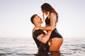 Happy young fit couple in the sea or ocean hug each other with love at summer sunset. Romantic mood, tenderness