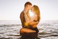 Happy young fit couple in the sea or ocean hug each other with love at summer sunset. Romantic mood, tenderness