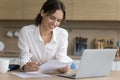 Happy young freelance business woman reading document at laptop